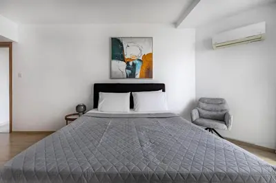 a bedroom with a bed and a chair at Marathon Beach Apartment - Sea View, Shared Pool in Limassol