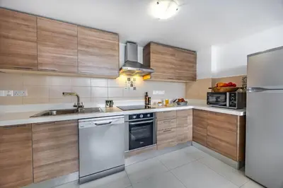 a kitchen with wooden cabinets and stainless steel appliances at Marathon Beach Apartment - Sea View, Shared Pool in Limassol