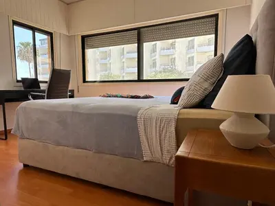 a bedroom with a large bed and two windows at Beachfront apartment with Kids Room, Pool & 2 Workspaces in Limassol