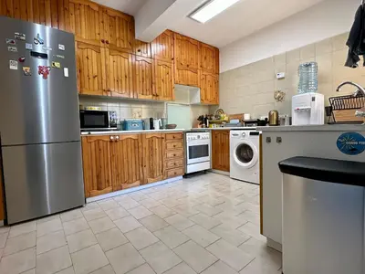 a kitchen with wooden cabinets and a stainless steel refrigerator at Beachfront apartment with Kids Room, Pool & 2 Workspaces in Limassol
