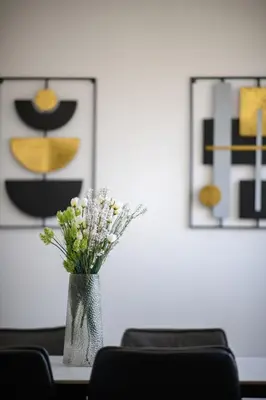a vase of flowers sitting on a table with two pictures at Ariel 3 bed Apartment in Larnaka