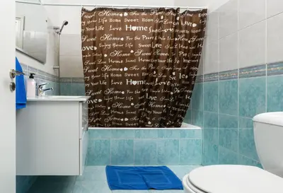 a bathroom with a shower curtain with writing on it at Ariel 3 bed Apartment in Larnaka