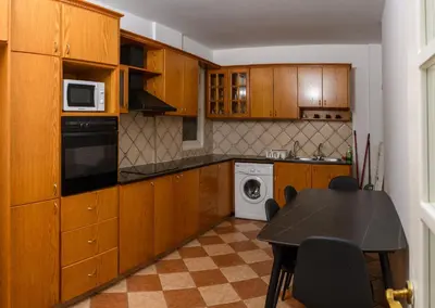 a kitchen with wooden cabinets and a table and a microwave at Ariel 3 bed Apartment in Larnaka