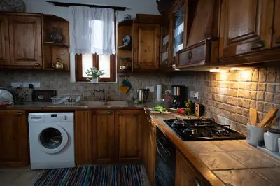 a kitchen with wooden cabinets and a washing machine at Apanemia Inn House in Lofou