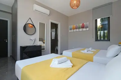 a bedroom with two beds and a bathroom with a mirror at Villa Camellia - 3bed Bungalow large pool in Protaras