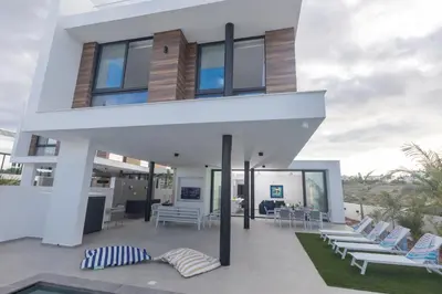 a house on the beach with chairs and a pool at Aqua 4 Bedrooms in Paralimni