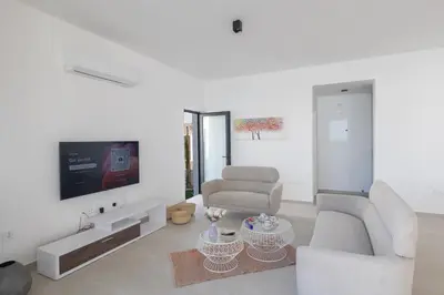a white living room with a couch and a tv at Aqua 4 Bedrooms in Paralimni