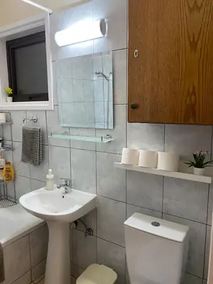 a bathroom with a sink and a toilet and a mirror at Kition Cozy Residence in Larnaka