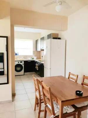 a kitchen with a wooden table and a white refrigerator at Cozy apartment in Larnaka