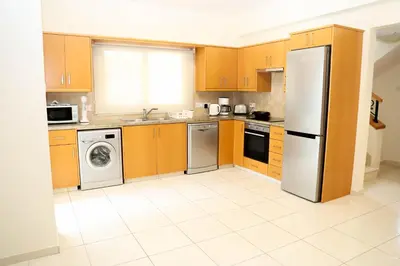 a kitchen with wooden cabinets and a refrigerator at Anthorina Villa 21 in Protaras