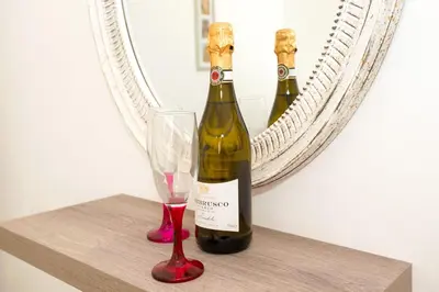 two bottles of wine on a shelf with a glass at Jules Apartment in Paralimni