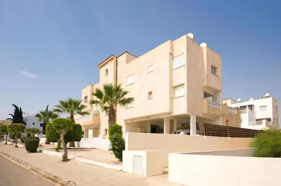 a building with palm trees in front of it at Jules Apartment in Paralimni