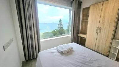 a bedroom with a large window with towels on a bed at Touch of class Molos Limassol in Limassol