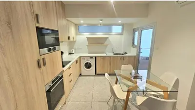 a kitchen with a glass table and a dining room at Touch of class Molos Limassol in Limassol