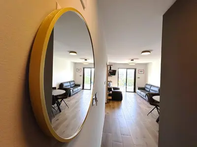 a mirror hanging on a wall next to a living room at THE A-LINE SEAVIEW MALAMA APARTMENT with pool, tennis court & gym in Paralimni