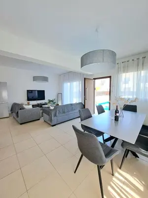 a living room with a table and a couch at SERENITY PEARL VILLA at the sea in Protaras