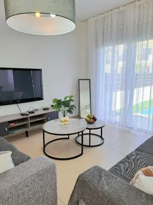 a living room with a couch and a table and a tv at SERENITY PEARL VILLA at the sea in Protaras