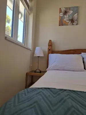 a bedroom with a bed and a lamp and a window at Kafkalia Sea Breeze in Larnaka
