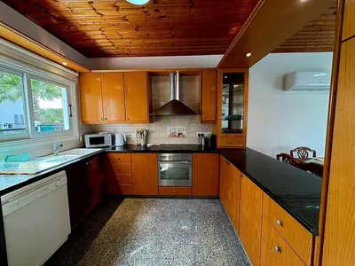 a kitchen with wooden cabinets and black counter tops at Villa Solmare in Pervolia