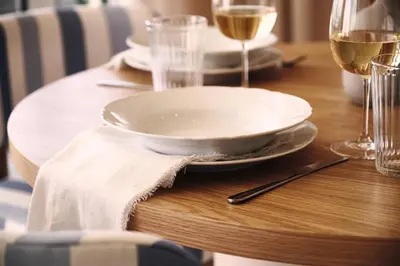 a wooden table with a white plate and glasses of wine at Suite 1003 at Althea Residence in Larnaka