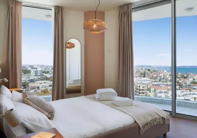 a bedroom with a bed and large windows at Suite 1003 at Althea Residence in Larnaka