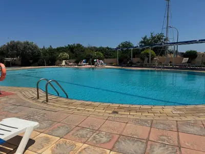 a large swimming pool with a white bench next to it at Protaras Sunset Bay in Protaras