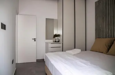 a white bedroom with a bed and a mirror at Le Bouquet Luxury Suites Ltd in Nicosia