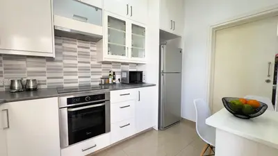 a kitchen with white cabinets and a black oven at Hills 2bdr Seaside Makenzy Larnaka in Larnaka