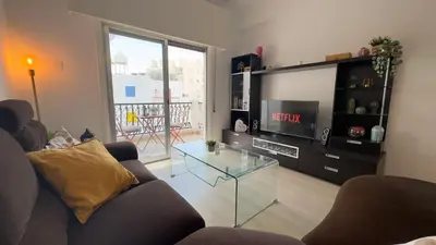 a living room with a tv and a glass table at Hills 2bdr Seaside Makenzy Larnaka in Larnaka