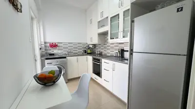 a white kitchen with a bowl of fruit on a table at Hills 2bdr Seaside Makenzy Larnaka in Larnaka