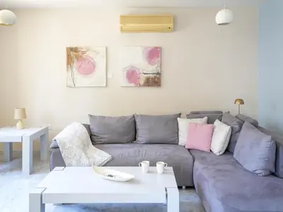 a living room with a gray couch and a white table at Mediterranean Escape - Coastal 2-Bedroom Apartment Limassol in Limassol