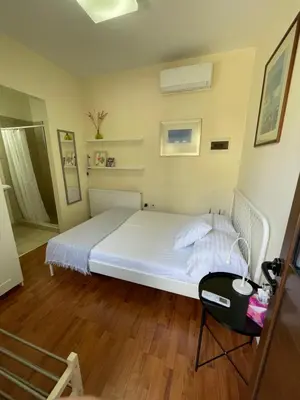 a bedroom with a large white bed and wooden floors at Yard room with private entrance in Larnaka