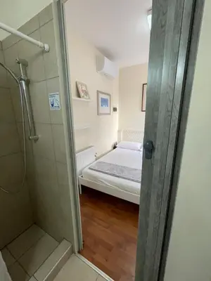 a small bedroom with a bed and a shower at Yard room with private entrance in Larnaka