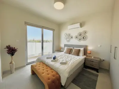 a bedroom with a large bed and a large window at STAY Mythical Blue Apartment in Protaras