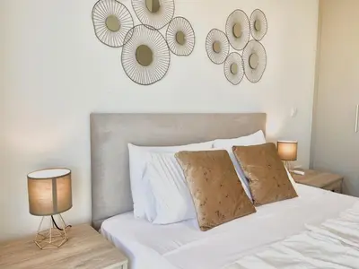 a bedroom with a white bed with two mirrors on the wall at STAY Mythical Blue Apartment in Protaras