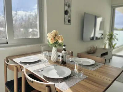 a dining room table with plates and a vase with flowers at STAY Mythical Blue Apartment in Protaras