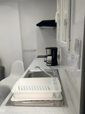 a kitchen counter with a white sink and a sink at Ermioni Apartments in Limassol