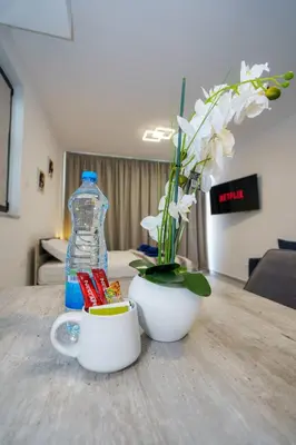 a bottle of water and a vase with flowers on a table at Seaview Suite49 steps to Mackenzie Beach Larnaca in Larnaka