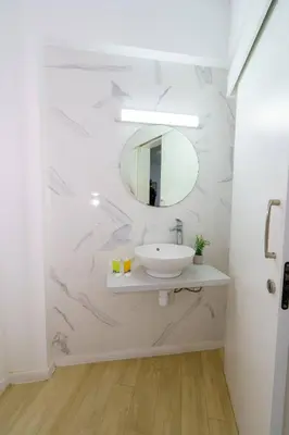 a white bathroom with a sink and a mirror at Kitieos 163 Suite in Finikoudes in Larnaka