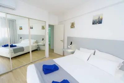 a bedroom with a white bed and a mirror at Kitieos 163 Suite in Finikoudes in Larnaka