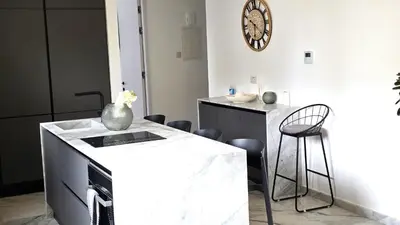 a kitchen with a white counter and a table and chairs at Luxurious 2BR Apartment in City Center with Internet in Larnaka