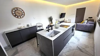 a kitchen with a sink and a living room at Luxurious 2BR Apartment in City Center with Internet in Larnaka