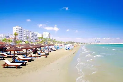 a beach with chairs and umbrellas and the ocean at Sunshine Escape in Larnaka