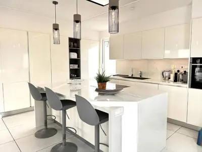 a kitchen with white cabinets and a white island with chairs at Sunset Family Villa w heated pool - 1Min Walk to Beach in Protaras