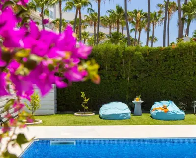 two pillows and a swimming pool with palm trees at Sunset Family Villa w heated pool - 1Min Walk to Beach in Protaras