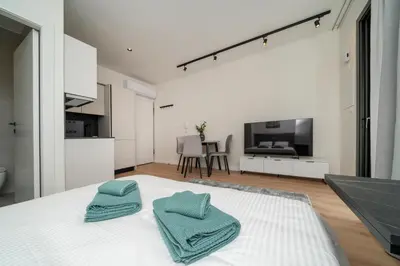 a white bedroom with two towels on a bed at Luxury Studio in the Heart of Limassol in Limassol