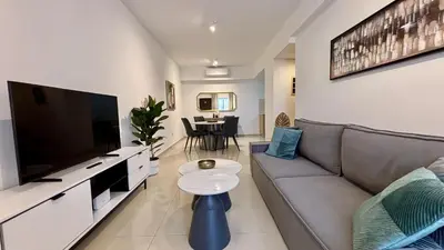 a living room with a couch and a flat screen tv at Zavos Aqua Park Club Apt by TrulyCyprus in Limassol