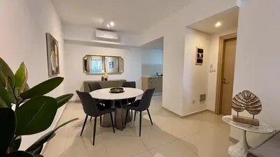 a dining room and living room with a table and chairs at Zavos Aqua Park Club Apt by TrulyCyprus in Limassol