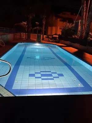 a swimming pool lit up at night with at Modern Holiday Appartment With Pool in Paralimni