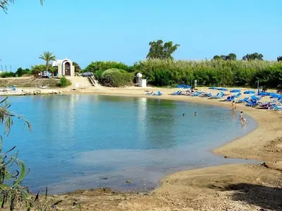 a beach with blue umbrellas and people in the water at Modern Holiday Appartment With Pool in Paralimni